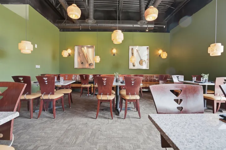 Exposed ceiling ductwork, multiple pendant light fixtures, wall-mounted art, built-in booth seating, and carpeted flooring