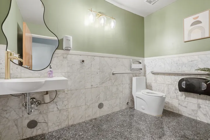 Full-height wall tiling, gold-finish faucet, and modern vanity with integrated sink