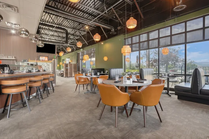 Expansive interior featuring large format windows, exposed ceiling trusses, a service counter, and contemporary lighting fixtures
