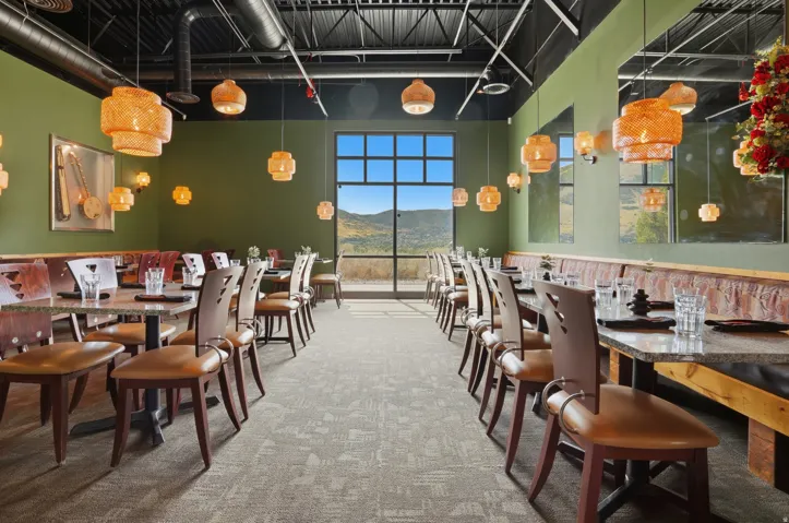 Exposed ceiling ducts and beams, recessed lighting, large window, granite-top tables, and banquette seating