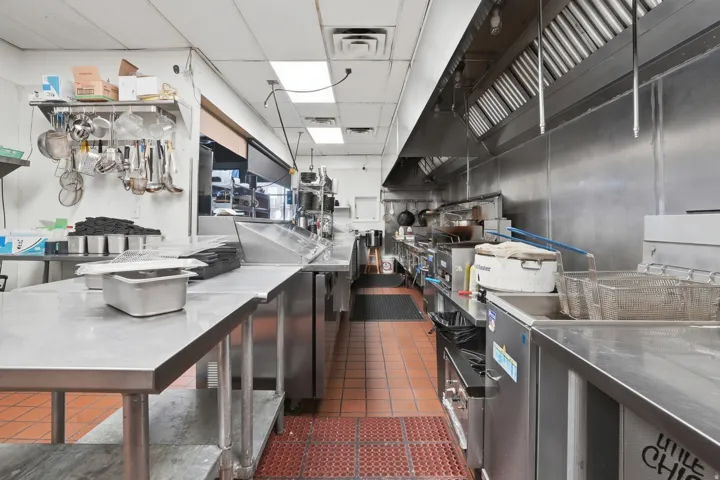 Commercial-grade kitchen featuring stainless steel countertops, stainless steel appliances, stainless steel wall panels, and tile flooring