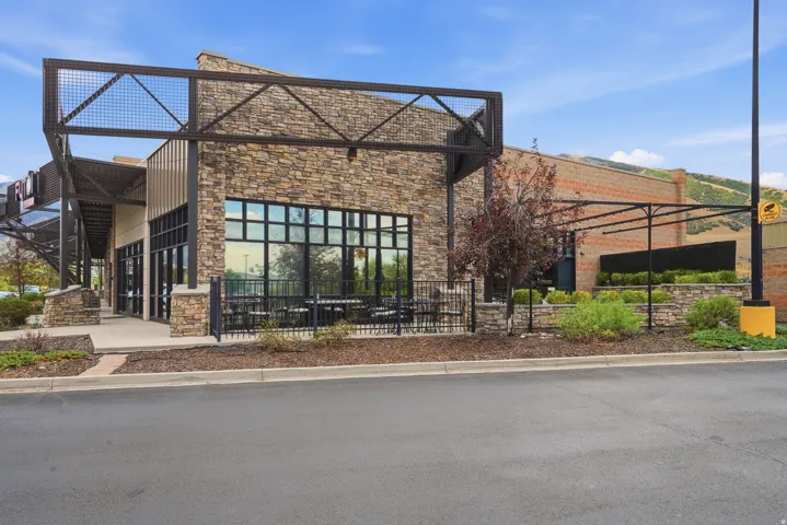 Stone veneer facade with large pane windows, complemented by black metal architectural elements