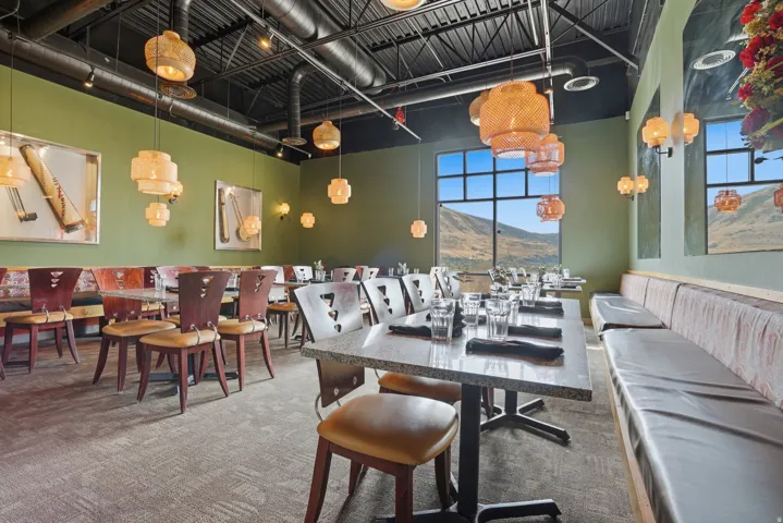 Open-concept dining area featuring suspended lighting, wall-mounted sconces, exposed ceiling ductwork, and large picture windows