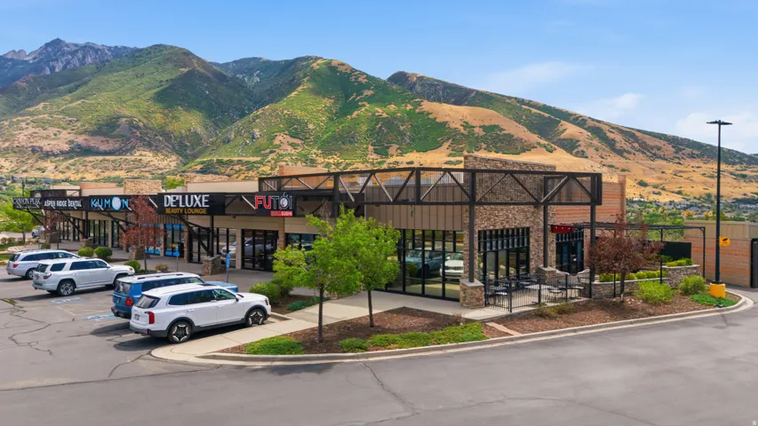 Retail building with stone and brick facade, large storefront windows, and visible mountain scenery