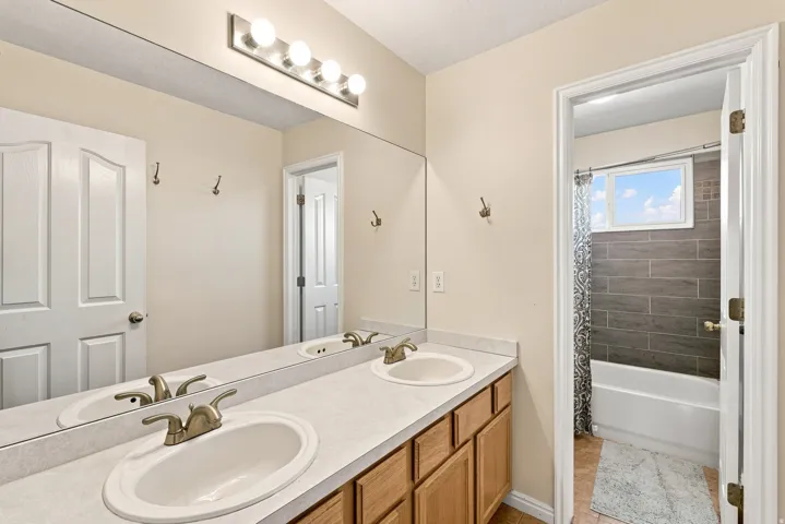 Double vanity with white oval sinks and brushed nickel faucets, set in a light-toned countertop