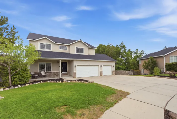 Two-story stucco residence with a covered front porch, an attached three-car garage, and a concrete driveway