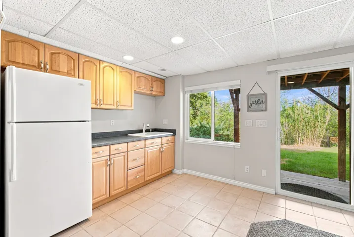 Kitchenette featuring a full-size refrigerator, wood cabinetry, and a ceramic tile floor