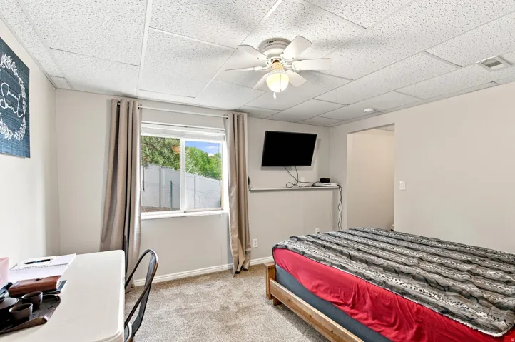 Drop ceiling with recessed lighting, ceiling fan, wall-mounted television, and wood-frame bed