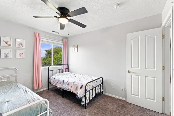Room featuring a ceiling fan with integrated lighting, carpeted flooring, and a window with natural light