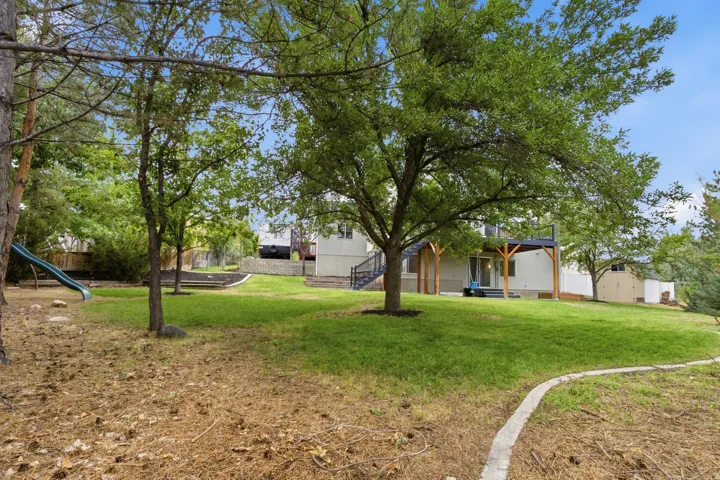 Sloping lawn with mature trees, a concrete border, and a raised wooden deck