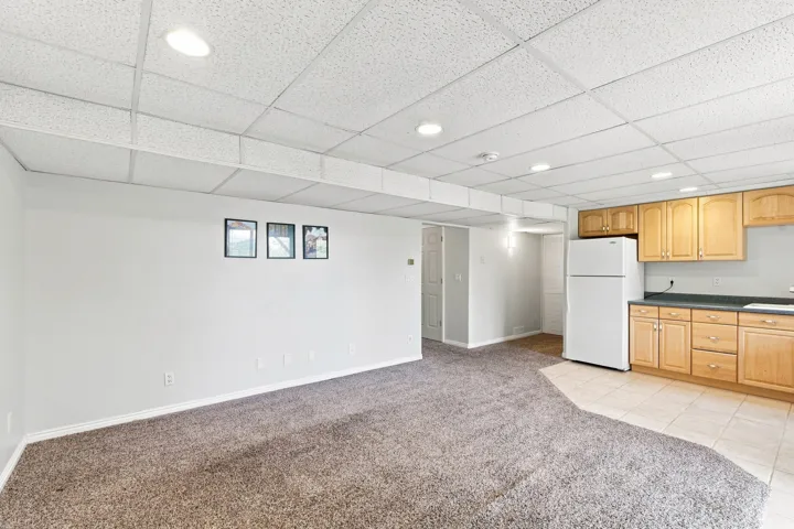 Recessed lighting, wood-finish cabinetry, tile flooring, carpeted area, and drop ceiling