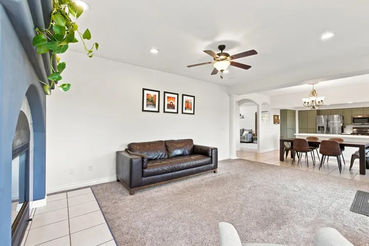 Recessed lighting, ceiling fan, arched doorway, tile flooring, and carpeted living space