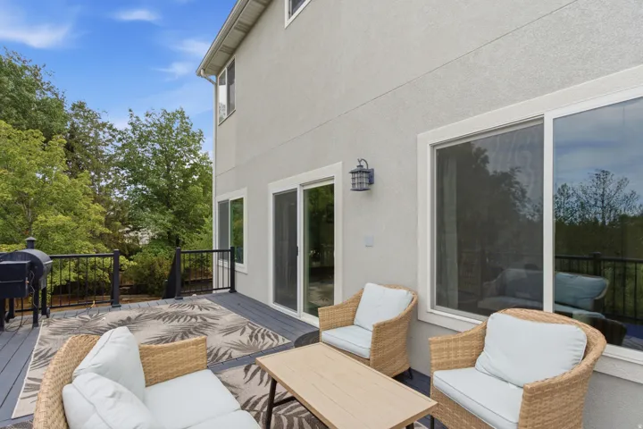 Exterior deck with a gray finish, black railings, and a stucco-finish facade