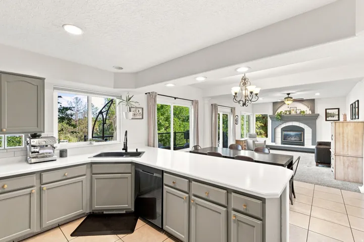Kitchen featuring light gray cabinetry, white countertops, subway tile backsplash, and a corner sink