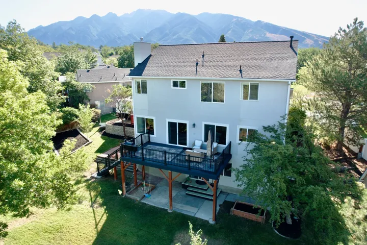 Rear elevation featuring a multi-level deck, sliding glass doors, and a secondary patio area