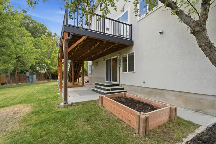 Multi-level deck with black railing and wood-finish underside, leading to a ground-level patio