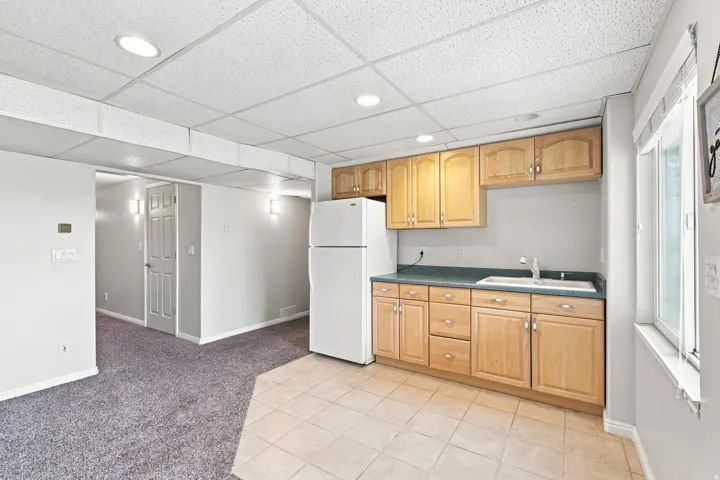 Kitchenette featuring wood-finish cabinetry, a white refrigerator, and a stainless steel sink