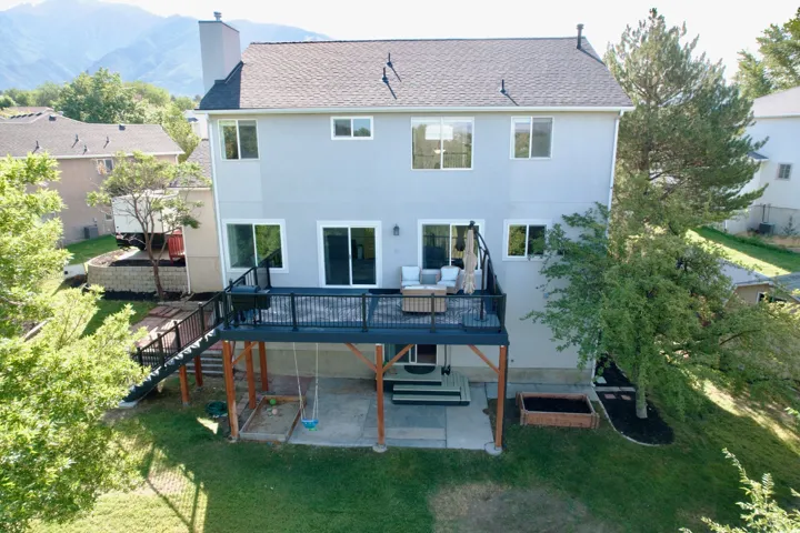 Rear elevation with a multi-level deck, mountain backdrop, and ground-level patio