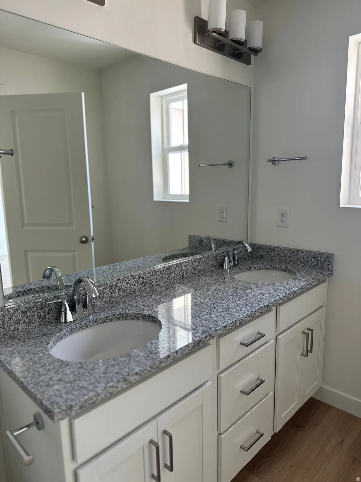 Dual vanity with granite countertops, undermount sinks, and white shaker-style cabinetry