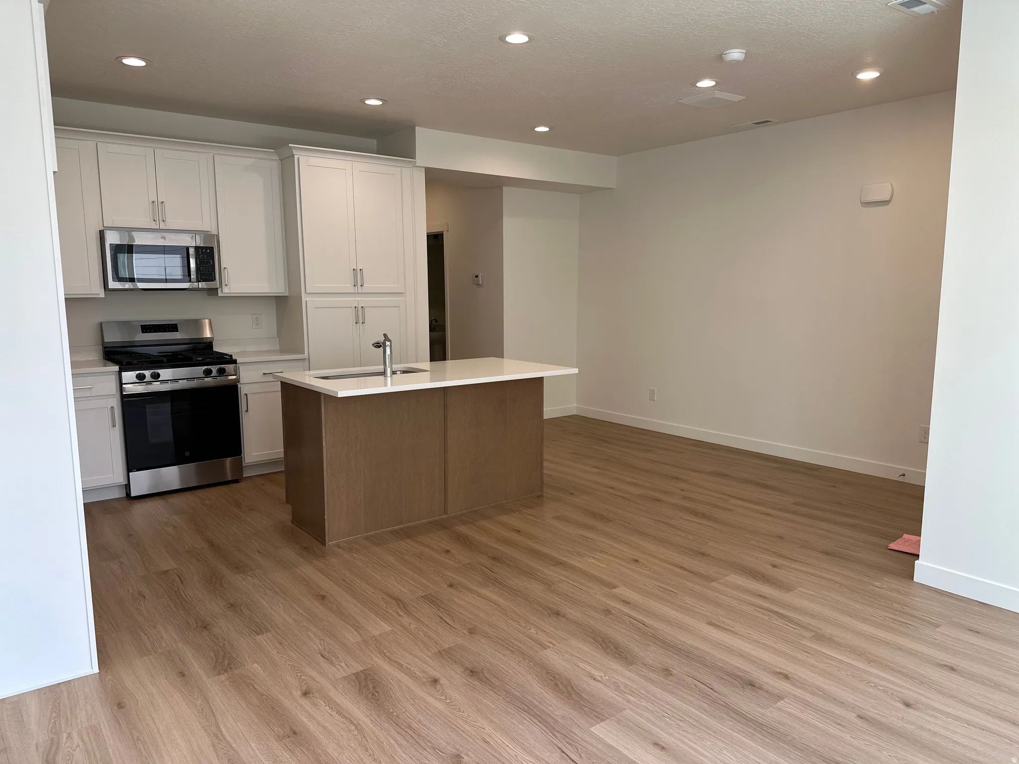 Kitchen with white cabinetry, stainless steel appliances, and a central island with an undermount sink