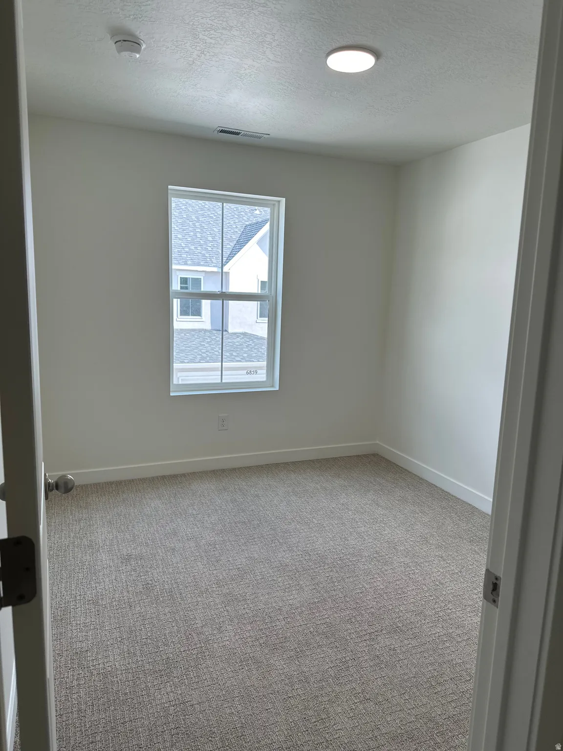 Neutral-toned textured carpeting, white walls, and a recessed ceiling light fixture