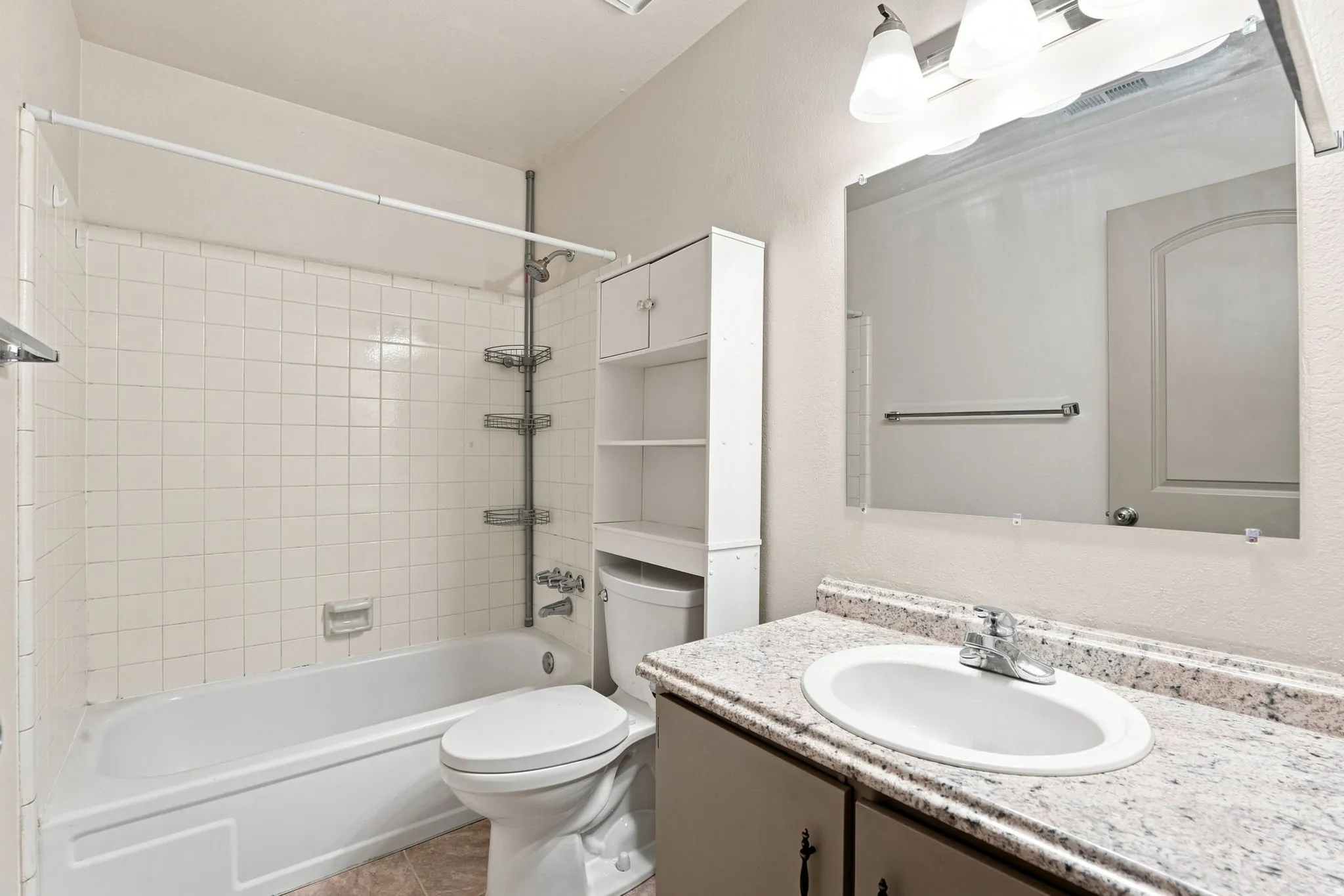 White tile shower surround, integrated bathtub, and chrome fixtures