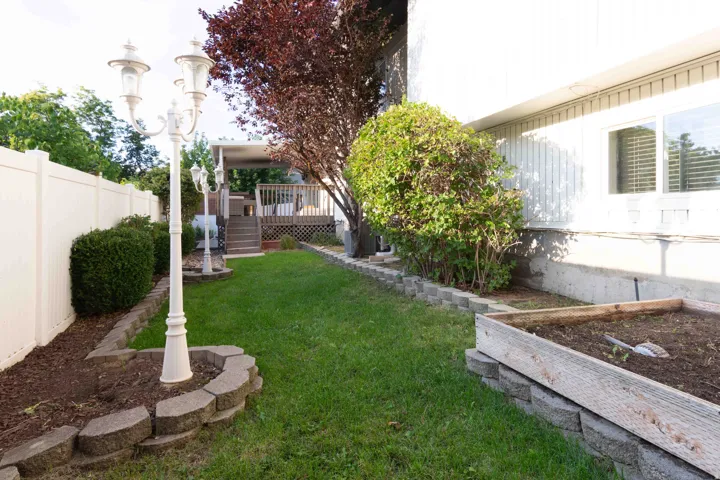 Manicured lawn with a white vinyl fence, decorative lamp post, and raised garden bed