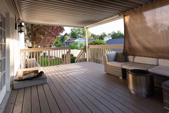Covered outdoor deck with wood-finish flooring, wood railings, and exterior wall-mounted lantern