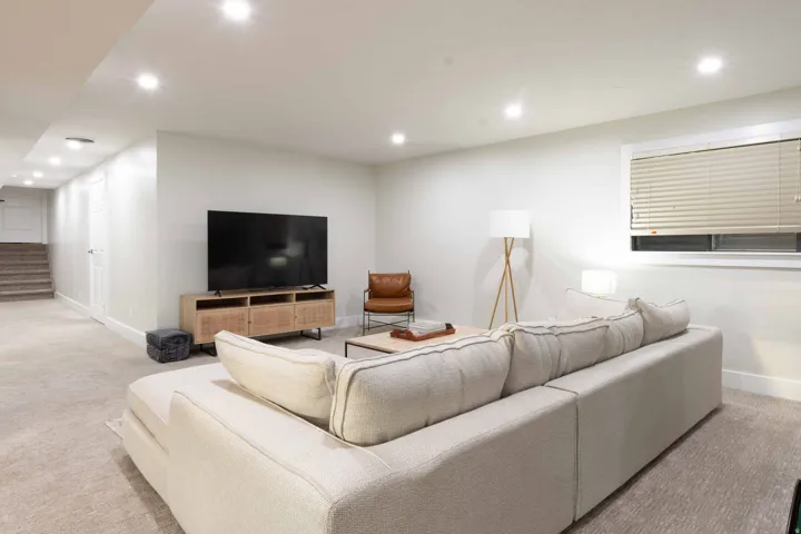 Recessed ceiling lighting illuminates the carpeted living area with a window providing ambient light