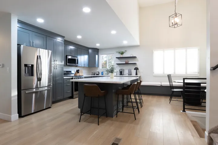 Modern kitchen featuring sleek gray cabinetry, stainless steel appliances, a center island with countertop seating, and light wood-finish flooring