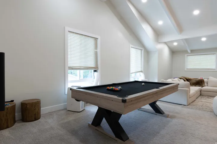Sloped ceilings with exposed beams, recessed lighting, carpeted flooring, and multiple windows with blinds