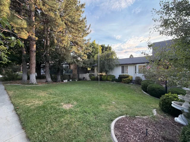 Manicured front lawn with mature trees and established landscaping