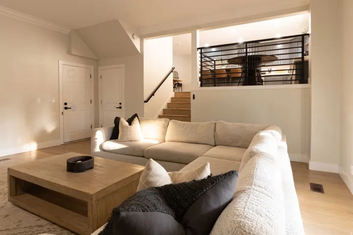 Wood-finish flooring throughout, white interior doors, and a staircase with a dark handrail