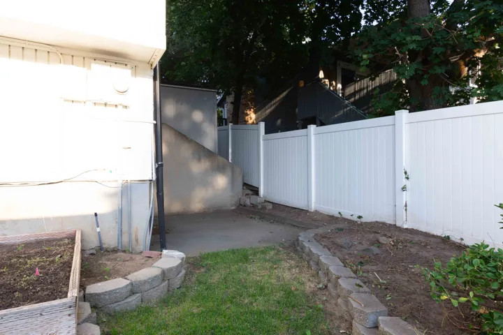 White vinyl fencing, concrete retaining wall, and landscaped planting beds