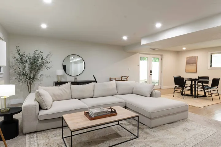 Recessed lighting illuminates an open-concept living area with light-toned walls and wood-finish flooring