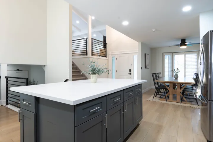 Kitchen island with white countertop, gray cabinetry, and stainless steel hardware