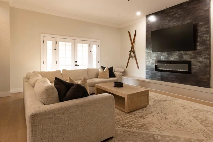 Wood-finish flooring, crown molding, and a modern fireplace with a textured accent wall and built-in media ledge