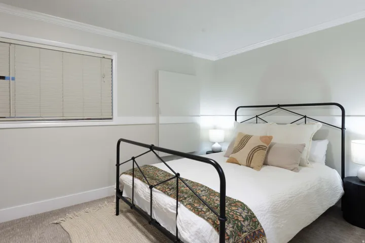 Crown molding, two-tone wall treatment, window with blinds, and carpeting