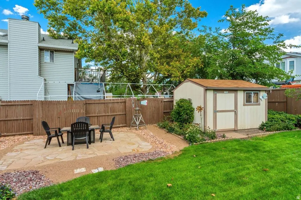 Expansive backyard featuring a manicured lawn, flagstone patio, gravel accents, and a functional storage shed