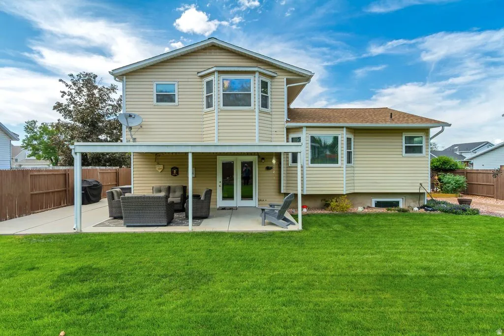 Expansive backyard featuring a lush lawn, concrete patio, and covered awning