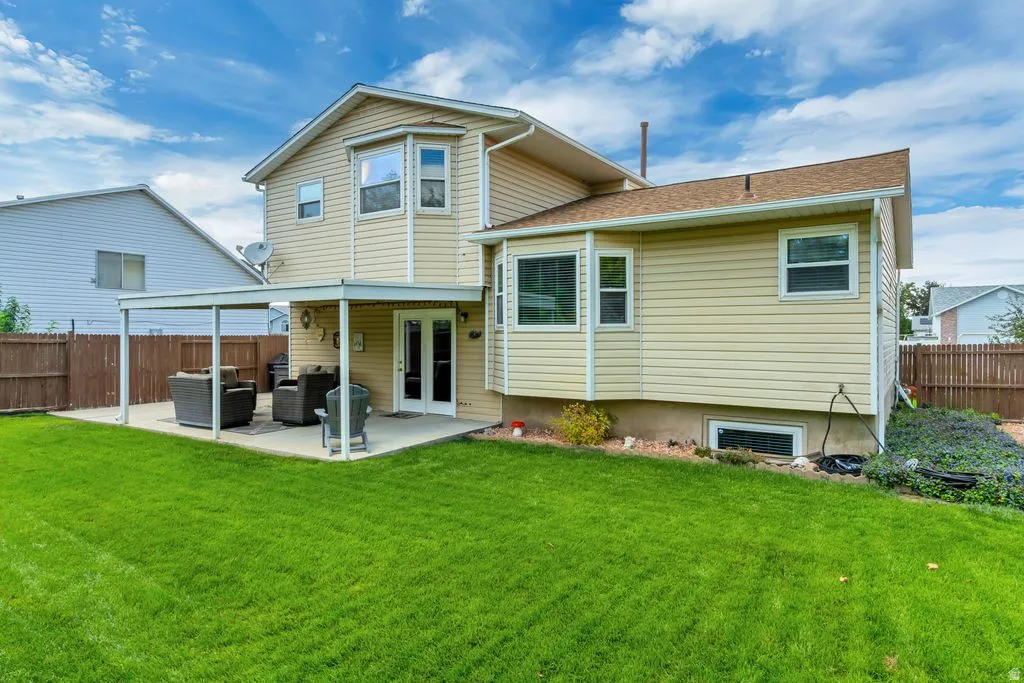 Expansive lawn with a concrete patio featuring an attached patio cover