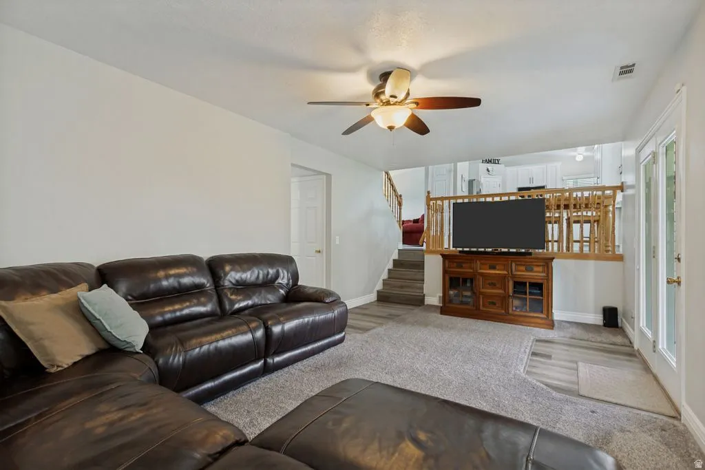 Recessed lighting, ceiling fan, wood-finish flooring, staircase with wood railing, double glass-paneled door