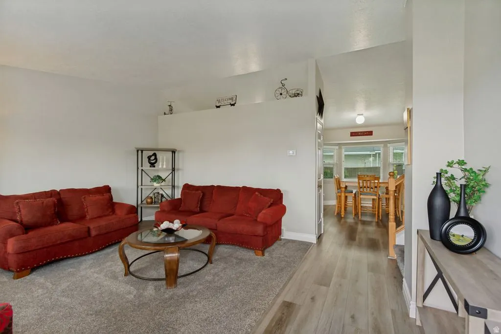 Vaulted ceiling with recessed lighting, wood-finish flooring, and neutral wall paint
