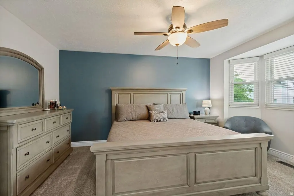 Recessed bay window, ceiling fan with integrated lighting, broad baseboards, and wall-to-wall carpeting