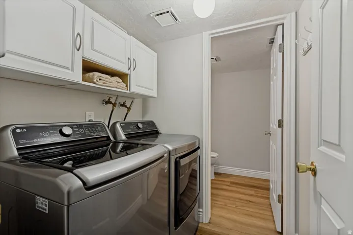 White shaker-style cabinetry with brushed nickel hardware, open shelving, and wood-finish flooring