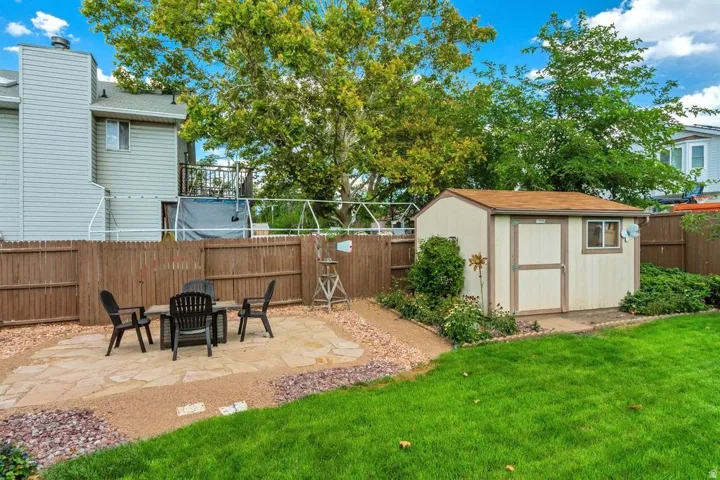 Expansive backyard featuring a manicured lawn, flagstone patio, gravel accents, and a functional storage shed