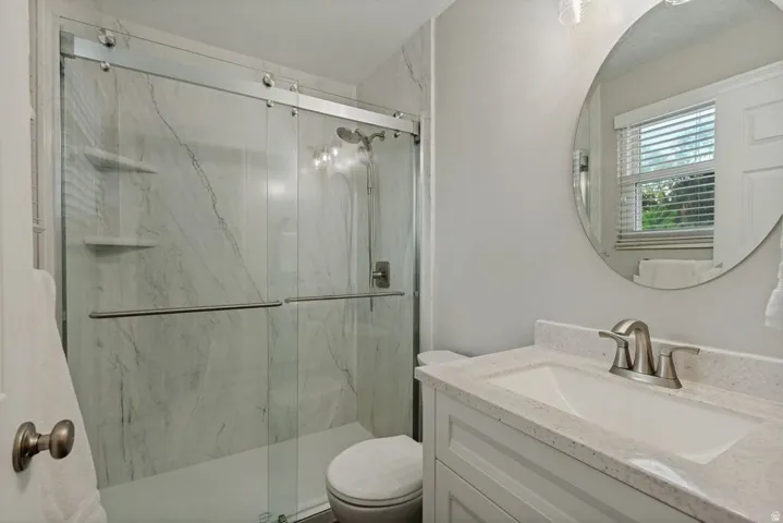 Glass-enclosed shower with marble-finish tile surround and built-in shelves