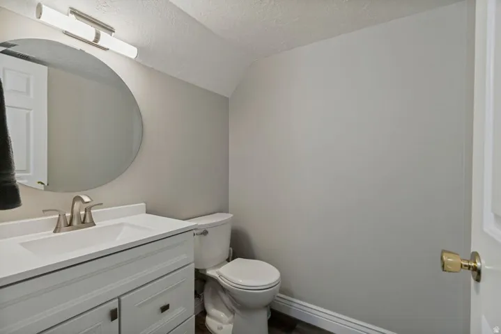 White vanity with integrated sink, brushed nickel faucet, round wall mirror, and overhead linear light fixture