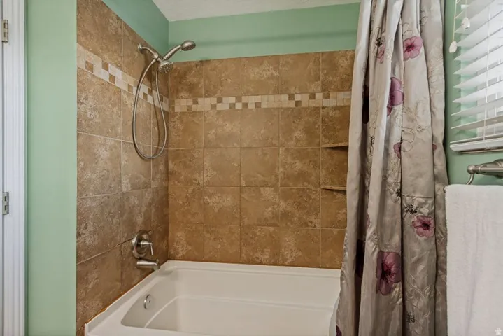 Tiled tub/shower combination with a decorative accent band and two recessed storage niches
