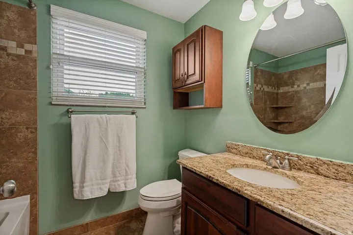 Vanity with a light-toned stone countertop and integrated oval sink